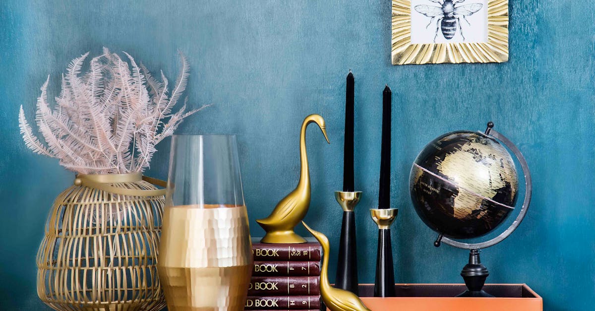 Stylish home decor arrangement including a globe, books, candles, and vases on a blue backdrop.